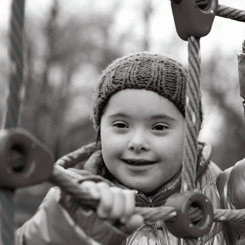 Little kid with Down Syndrome climbing rope ladder.
