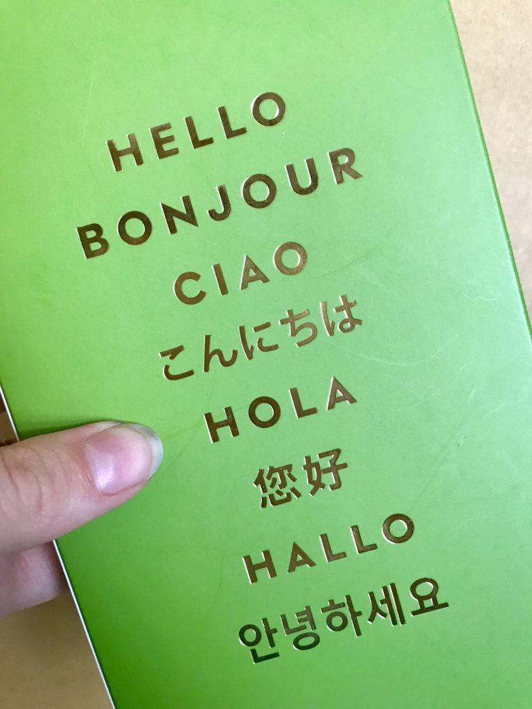 Hand holding a sign that says hello in multiple languages