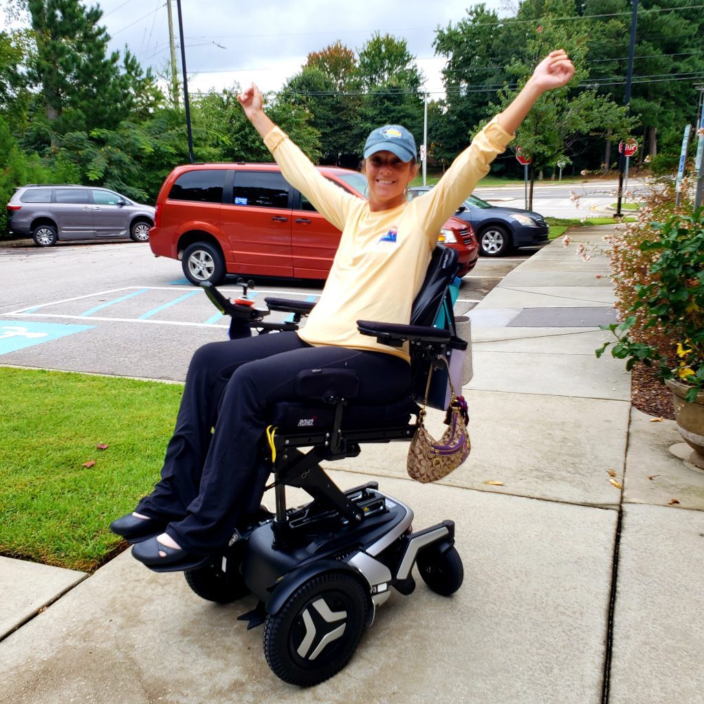 Ali Ingresoll with her arms raised on a specialized wheelchair. 